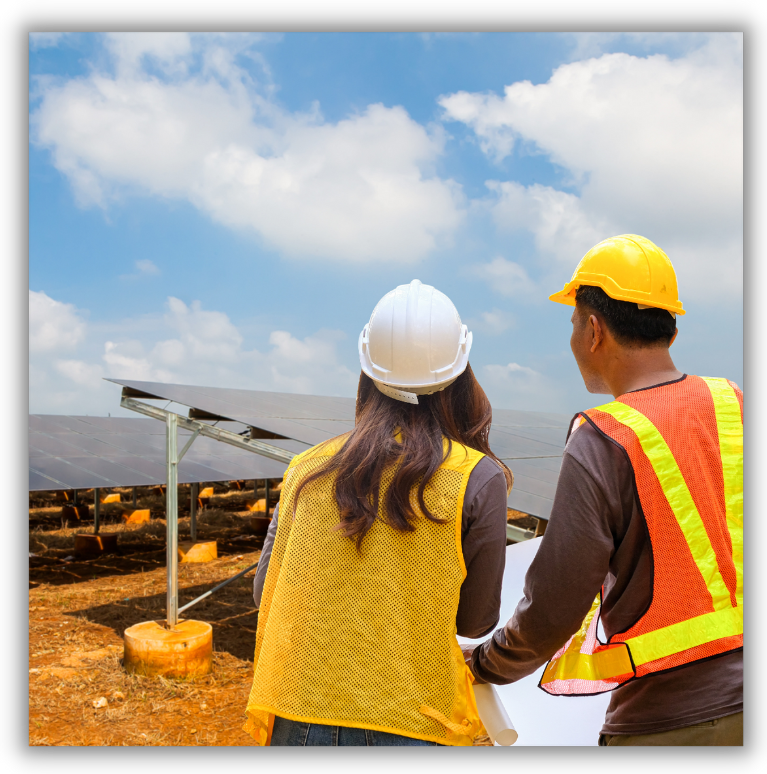 Two people in hard hats looking at a field of solar panels